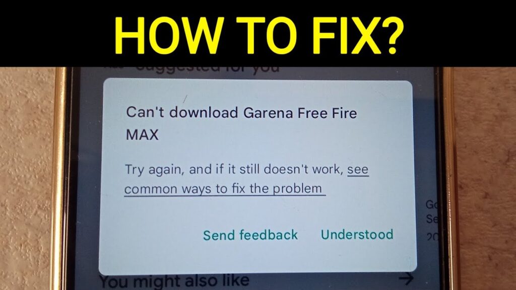 A smartphone screen displays an error message that reads, "Can't download Garena Free Fire MAX." The message suggests trying again and offers a link to common troubleshooting methods for installing apps. Options to "Send feedback" and "Understood" are also available. Text at the top reads, "HOW TO FIX?”.